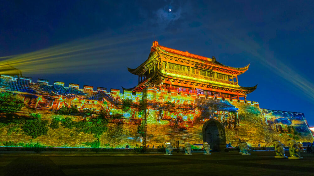 夜幕降临,从水亭门对岸打出了一束束光柱,巨大的光柱像一把把巨大的银色长剑,刺破夜空。音乐响起,南孔家庙、龙游石窟、江郎山、红木小镇、廿八都、根宫佛国等衢州美景美丽大花园、活力新衢州等文字图片,乘着万道虹霓出现在帆船大屏幕上,似披着五彩云裳的霞帔飘然而至。
